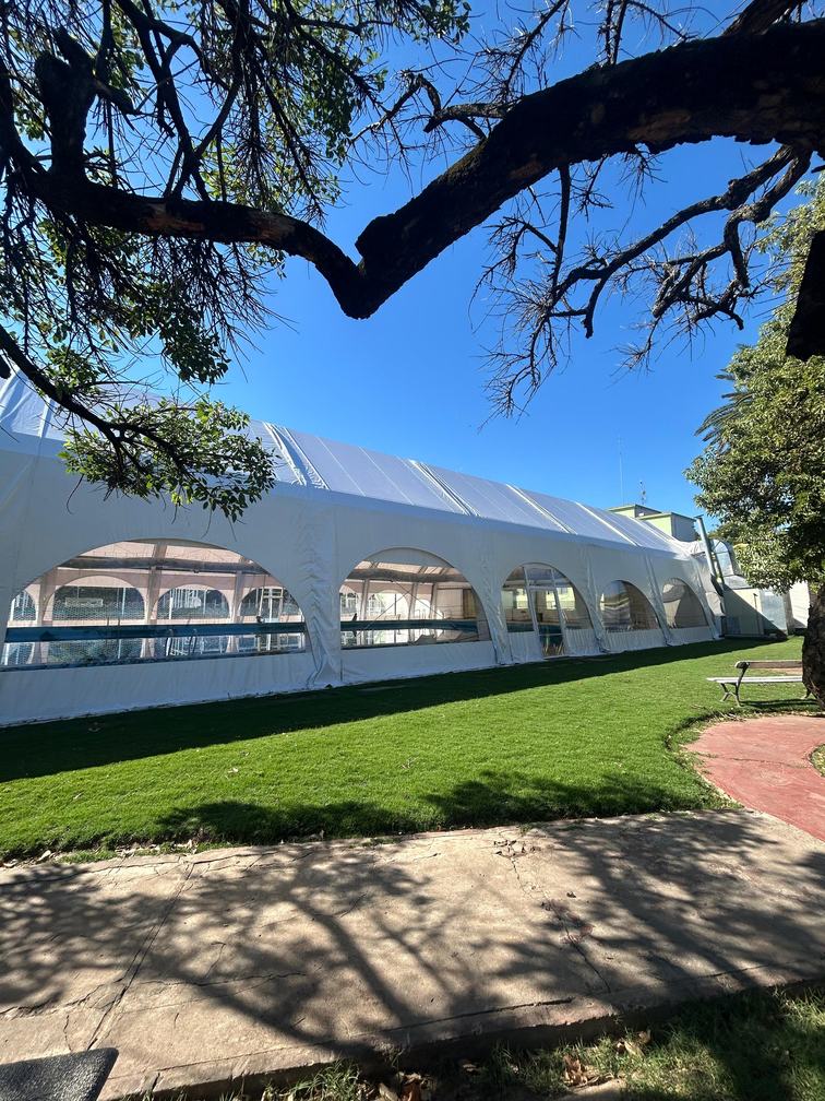 Vista exterior de la carpa de lona blanca con aberturas en PVC cristal a lo largo del lateral