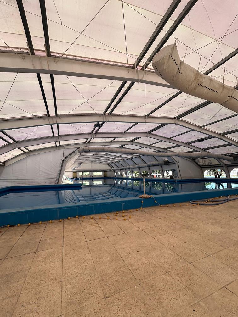 Interior de la carpa sobre la pileta olímpica, con la estructura, la cubierta de lona y las mangas de climatización