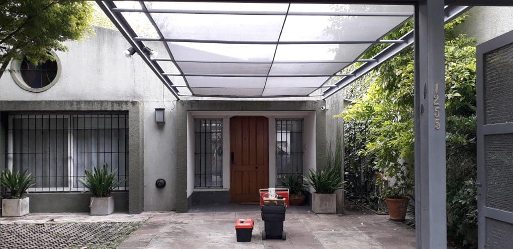 Cochera con techo traslúcido sobre la entrada, realizada por Lonera San Román